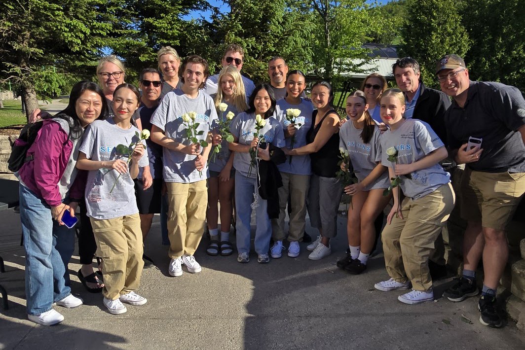 Graduating Stouffville Academy students and their families holding white roses outdoors